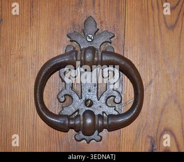 Antica porta di ferro che bussa su una porta di legno rustica Foto Stock