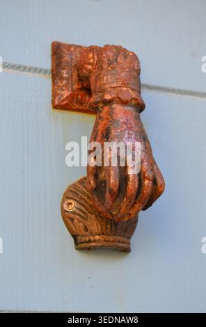 Antica porta di ferro a forma di mano che bussa su una porta di legno dipinta di blu Foto Stock