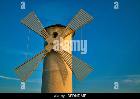 Storico Faro bianco e Torre del mulino a vento con vele in legno contro il cielo azzurro al tramonto - la città costiera di Świnoujście. Foto Stock