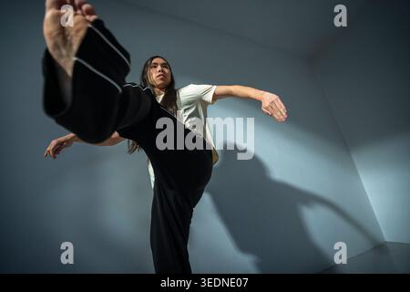 Vista ad angolo basso di una determinata persona non binaria che pratica danza contemporanea vicino al muro Foto Stock