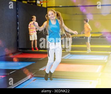 Ragazza teen che salta sul trampolino sul parco giochi gonfiabile interno Foto Stock