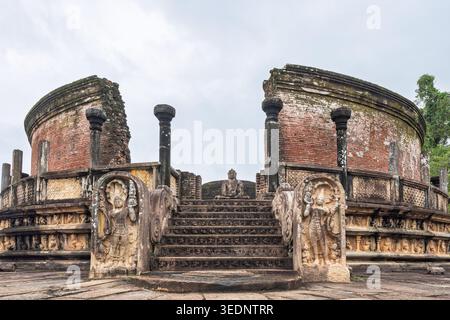 Polonnaruwa, Sri Lanka - 29 dicembre 2025: Antiche rovine di un tempio circolare con muri in mattoni rossi e gradini di pietra che conducono ad una statua di Buddha, un Foto Stock