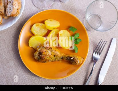 Coscia di pollo servita con patate sul piatto della cena Foto Stock