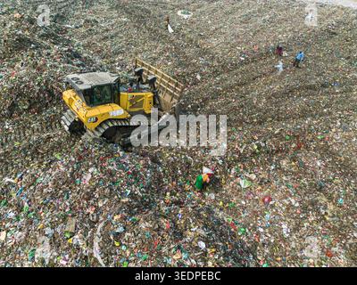 Aminbazar, Bangladesh - 26 gennaio 2025: Veduta aerea di un bulldozer giallo che muove pile di rifiuti di plastica e rifiuti presso la discarica di Aminbazar con wa Foto Stock