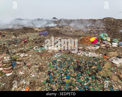 Aminbazar, Bangladesh - 26 gennaio 2025: Veduta aerea della discarica di Aminbazar con fumo che sale da mucchi di rifiuti e persone che scavano attraverso gar Foto Stock