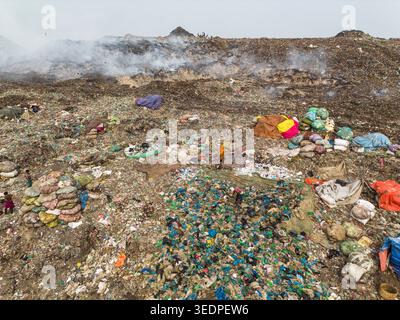 Aminbazar, Bangladesh - 26 gennaio 2025: Veduta aerea della discarica di Aminbazar con lavoratori che scavano tra vaste pile di rifiuti e fumo che fuoriesce Foto Stock