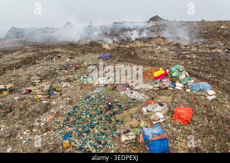 Aminbazar, Bangladesh - 26 gennaio 2025: Veduta aerea della discarica di Aminbazar con fumo proveniente da pali di rifiuti e raccoglitori di rifiuti che lavorano tra colo Foto Stock