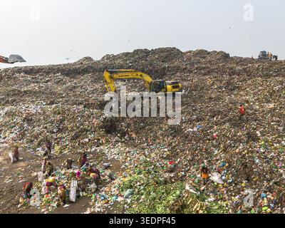 Aminbazar, Bangladesh - 26 gennaio 2025: Veduta aerea della discarica di Aminbazar con escavatori gialli che trasportano rifiuti e molte persone che scavano attraverso Foto Stock