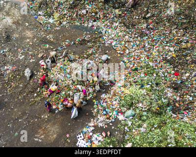 Aminbazar, Bangladesh - 26 gennaio 2025: Veduta aerea dei raccoglitori di rifiuti che smistano tra rifiuti organici e plastica colorati presso la discarica di Aminbazar. Foto Stock