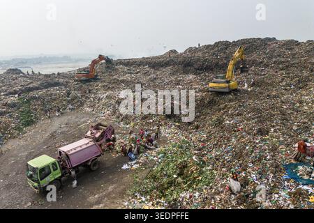 Aminbazar, Bangladesh - 26 gennaio 2025: Veduta aerea della discarica di Aminbazar con escavatori e persone che scavano attraverso enormi cumuli di rifiuti Foto Stock