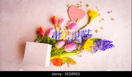 Natura morta con colorati fiori primaverili per la festa della mamma su tenero sfondo rosa per i saluti della festa della mamma. Foto Stock