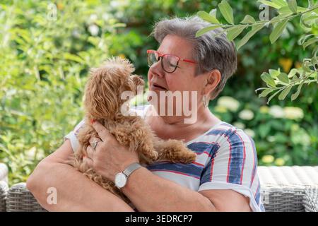 Ritratto di una donna con un maltipoo sul braccio Foto Stock