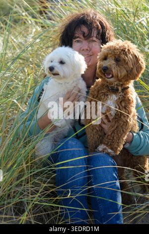 Ritratto di una donna con i suoi maltesi e Maltipoo nelle dune di Cuxhaven Foto Stock