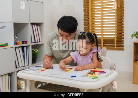 padre e bambina disegnano e dipingono con colori pastello ad olio su carta a casa Foto Stock