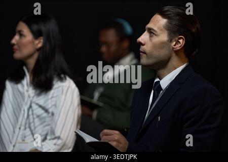 Professionisti aziendali che partecipano a conferenze e prendono appunti Foto Stock