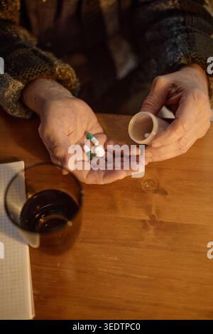 Persona anziana che tiene in mano le pillole di prescrizione per la routine dei farmaci a domicilio Foto Stock