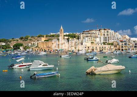 Marsaskala Marina con vista sulla chiesa parrocchiale di Sant'Anna in una mattinata di cielo azzurro. Malta. Foto Stock