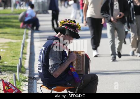 Musicista di strada a Barcellona, in Spagna, identificabile dal suo caratteristico cappello nero adornato da un vivace anello di fiori Foto Stock