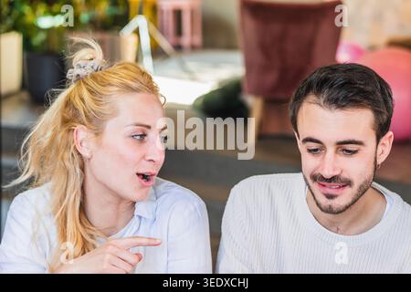 Due giovani professionisti impegnati in discussioni e lavoro di squadra in un ambiente di ufficio moderno Foto Stock