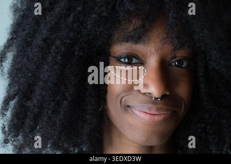 Donna con capelli afro che ha sotto gli occhi cerchi evidenziati per il concetto di cura della pelle Foto Stock
