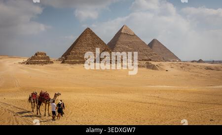 Complesso delle piramidi di Giza in Egitto, vista dal deserto con un giro in cammello intorno alle piramidi. Foto Stock