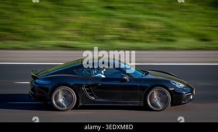 Black Porsche Cayman, auto in corsa verso la luce del mattino, M65 Altham, Lancashire, Inghilterra Foto Stock