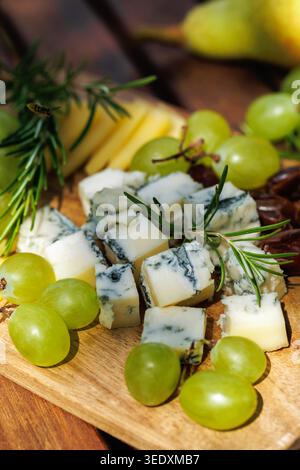 Piatto rustico di formaggi con uva ed erbe aromatiche. Foto Stock