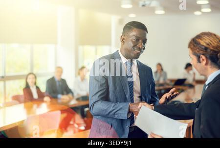 Manager africano di mezza età che dà il benvenuto a un nuovo dipendente bianco Foto Stock