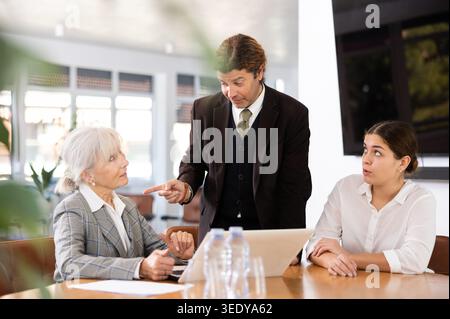 Uomo d'affari che discute il progetto durante un incontro di lavoro con i colleghi Foto Stock