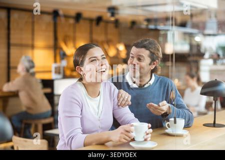 Uomo e donna allegri che si godono la data in un accogliente caffè Foto Stock