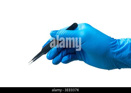 Primo piano della mano in un guanto in nitrile blu che regge pinzette in metallo nero su sfondo bianco. Foto Stock