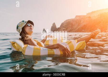Donna, spiaggia, galleggiamento rilassante su rafting gonfiabile giallo e bianco in acque cristalline. Foto Stock