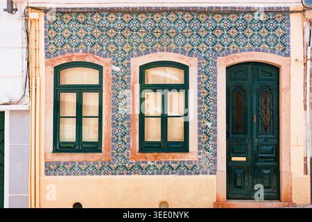 Lisbona, Portogallo: Facciata tradizionale con piastrelle azulejo blu, porta verde in legno e finestre ad arco nel quartiere di Alfama. Background dell'architettura. Foto Stock