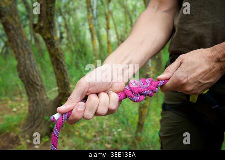 Primo piano di un arrampicatore che annoda la corda all'imbracatura Foto Stock