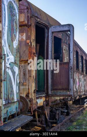 Vagone ferroviario d'epoca arrugginito abbandonato su vecchi binari ferroviari Foto Stock