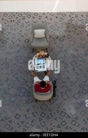 Vista dall'alto dell'uomo che utilizza un computer portatile al Dubai Mall, Emirati Arabi Uniti Foto Stock