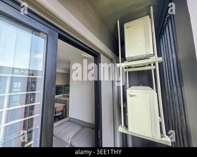 Due compressori per aria condizionata all'aperto montati in modo sicuro su un rack metallico all'esterno del moderno balcone di appartamenti residenziali che mostra una vita tranquilla e tranquilla Foto Stock