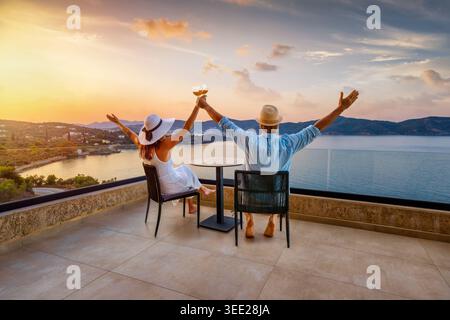 Una coppia felice di vacanze gode dello splendido tramonto estivo nel mediterraneo con un bicchiere di vino come concetto per un viaggio romantico Foto Stock