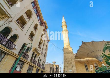 Una vista dall'angolo basso di uno storico minareto e degli edifici tradizionali del famoso mercato di Khan el-Khalili al Cairo, in Egitto, sotto un cielo azzurro. Foto Stock