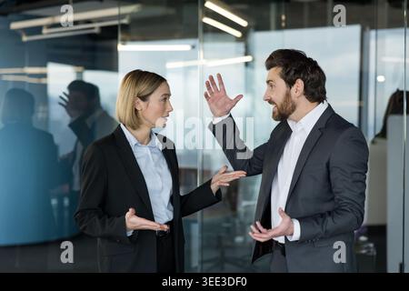 Due colleghi aziendali si sono impegnati in un acceso dibattito in ufficio, esprimendo frustrazione e incomprensione, portando a conflitti sul luogo di lavoro e sfide di comunicazione Foto Stock