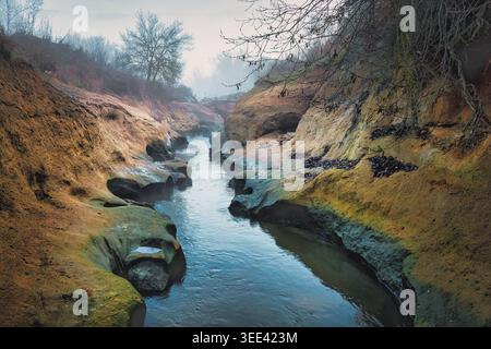 Gola nebbiosa del fiume con acqua turchese che scorre tra formazioni rocciose lisce ed erose. Foto Stock