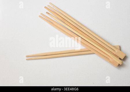 Bacchette di bambù tradizionali posizionate su un tavolo bianco pulito, composizione minimale ed elegante con texture naturale. Perfetto per i concetti Foto Stock