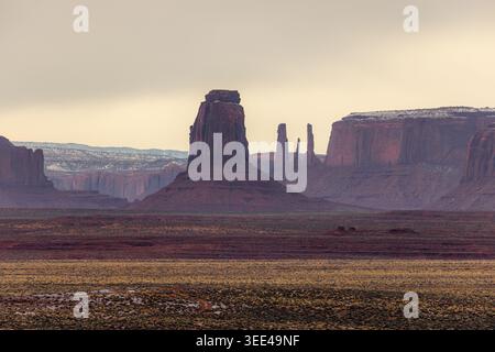Vista delle iconiche punte di arenaria rossa della Monument Valley sotto un cielo coperto con neve leggera su mesa lontane nella Oljato-Monument Valley, Arizona, Foto Stock