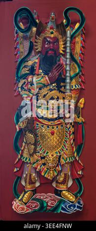 Genting Highlands, Pahang, Malesia - 22 febbraio 2025: Intricato pannello porta di una divinità colorata con faccia rossa, armatura dorata e arma nella sala della divinità della luce universale, il Tempio delle grotte di Chin Swee Foto Stock