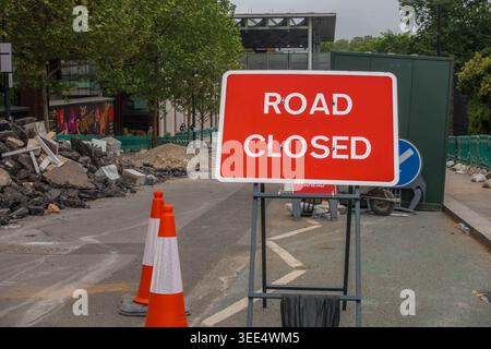 Un cartello stradale chiuso dall'altra parte della strada nella zona di King Cross di Londra con un mucchio di macerie. Foto Stock
