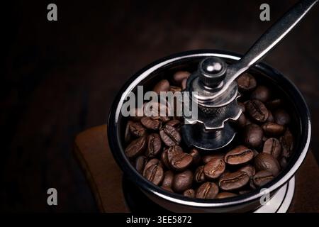 foto ravvicinata dei chicchi di caffè in una macchina per macinacaffè manuale con sfondo scuro Foto Stock