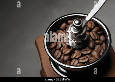 foto ravvicinata dei chicchi di caffè in una macchina per macinacaffè manuale con sfondo scuro Foto Stock