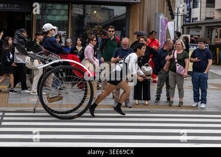 Tokyo, Giappone. 15 aprile 2026. Un risciò che trasporta un turista guida lungo la strada vicino alla porta Kaminarimon (porta del tuono) del Tempio Sensoji nel quartiere Asakusa della città di Tokyo, in Giappone Foto Stock