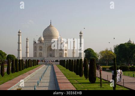 Mausoleo del Taj Mahal ad Agra in India caratterizzato da un'architettura in marmo bianco con fontane da giardino e turisti al tramonto Foto Stock
