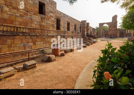Le storiche mura in pietra e le antiche rovine all'interno del complesso Qutub Minar a Delhi, India, mostrano la tradizionale architettura indo-islamica sotto un cielo limpido Foto Stock